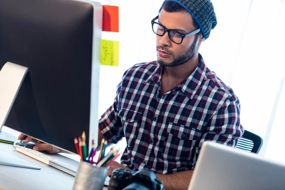 Freelance Web developer working at computer desk in studio.